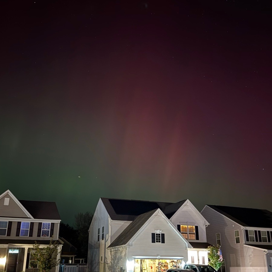 Red and green aurora above homes in a New Jersey neighborhood